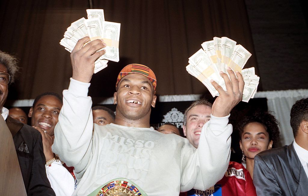 Dlaczego Mike Tyson zbankrutował? Zdjęcie przedstawia Mike'a Tysona z pakietami studolarówek w otoczeniu promotora Dona Kinga oraz bliższych i dalszych znajomych